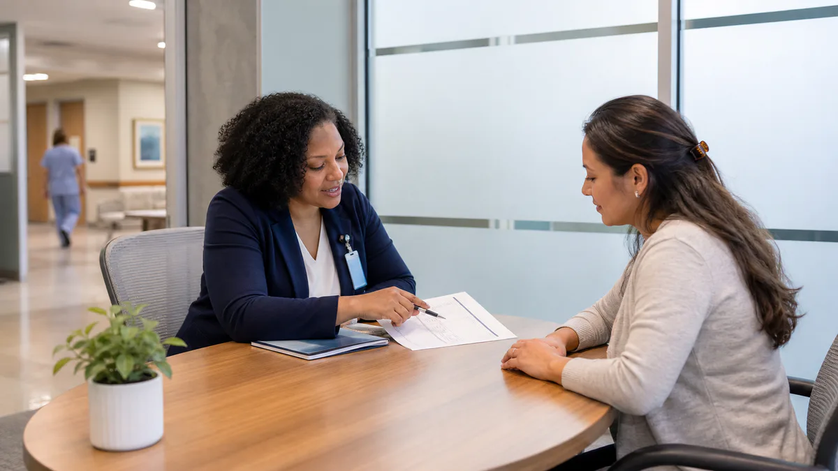 A hospital financial counselor reviews an assistance form with a patient in a private office.